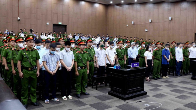 Photo diffusée par l'Agence vietnamienne d'information (VNA) le 28 juillet 2023 montrant des accusés (en chemises civiles) debout pour être condamnés lors du procès du vol à Hanoï. 