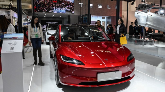 Les gens essayent la voiture électrique Model 3 de Tesla sur son stand lors de la China International Supply Chain Expo (CISCE) à Beijing le 1er décembre 2023.