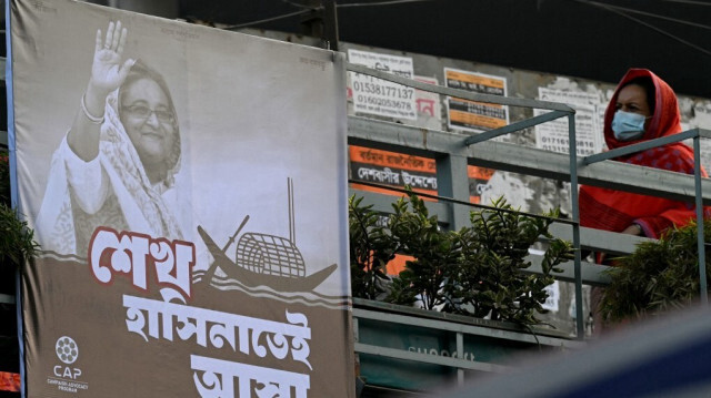 Un piéton passe devant une affiche électorale de la Ligue Awami mettant en vedette leur leader et le Premier ministre du Bangladesh, Sheikh Hasina, installée sur un pont piétonnier avant les prochaines élections générales, à Dhaka le 4 janvier 2024. 