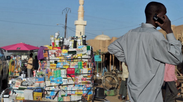 Un homme utilise son téléphone près d'un stand de produits pharmaceutiques sur un maket à Agadez, dans le nord du Niger.