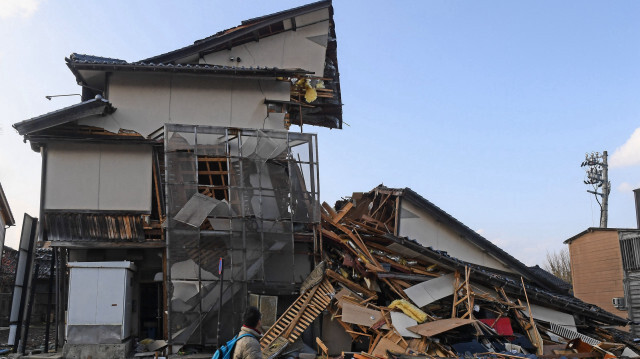 Un homme passant devant des bâtiments effondrés à Wajima au Japon, dans la préfecture d'Ishikawa, le 6 janvier 2024, après le séisme de magnitude 7,5 qui a frappé la région de Noto le jour de l'an.