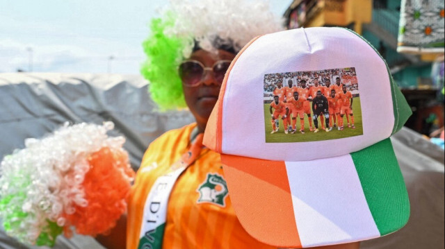 Un vendeur tient un chapeau avec une photo de l'équipe nationale de football de la Côte d'Ivoire imprimée au marché principal d'Adjamé à Abidjan le 9 janvier 2024, en préparation de la Coupe d'Afrique des Nations (CAN) 2024. 