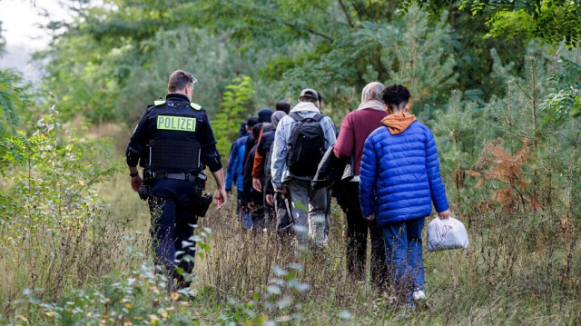 Un officier de la police fédérale allemande escorte un groupe de migrants près de Forst, dans l'est de l'Allemagne, le 11 octobre 2023, lors d'une patrouille près de la frontière avec la Pologne.