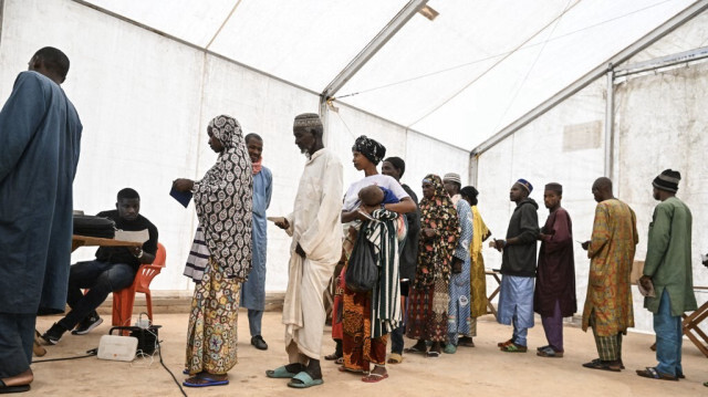 Des réfugiés du Burkina Faso font la queue pour recevoir une petite allocation mensuelle distribuée conjointement par le Programme alimentaire mondial (PAM) et le Haut Commissariat des Nations Unies pour les réfugiés (HCR) au camp de réfugiés de Niornigue, dans la ville de Ouangolodoudou, au nord de la Côte d'Ivoire, le 25 septembre 2024.