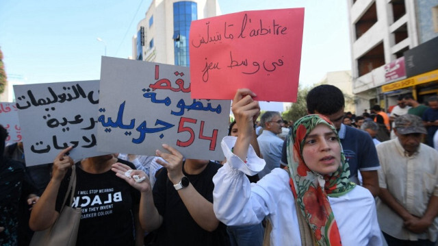 Des Tunisiens scandent des slogans et brandissent des pancartes lors d'une manifestation contre leur président et contre un projet de réforme électorale, le 27 septembre 2024, devant le parlement à Tunis.