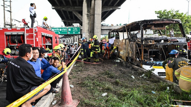 Des pompiers et des secouristes se tiennent à côté d'un bus incendié qui transportait des étudiants et des enseignants dans la banlieue de Bangkok, le 1er octobre 2024.