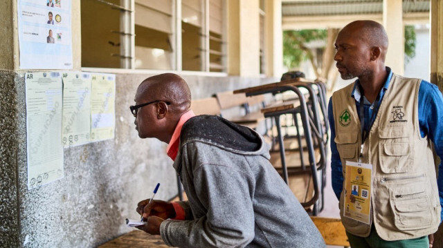 Deux hommes examinent les résultats affichés à l'extérieur d'une salle de classe utilisée comme bureau de vote à Beira, le 10 octobre 2024, au lendemain des élections nationales au Mozambique.