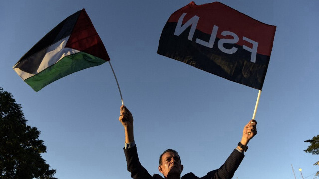 Un homme brandit des drapeaux palestinien et sandiniste lors de l'inauguration de la rue Gaza en soutien au peuple palestinien, dans le centre historique de Managua, le 30 janvier 2024.