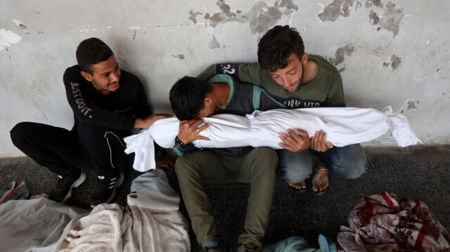 Ali Assaf (C), 20 ans, apparemment le seul survivant de sa famille tué lors d'une frappe aérienne israélienne dans le camp de réfugiés de Jabalia, dans le nord de la bande de Gaza, est réconforté par deux jeunes hommes alors qu'il pleure près des corps de ses proches devant l'église al-Maamadani, le 12 octobre 2024. 