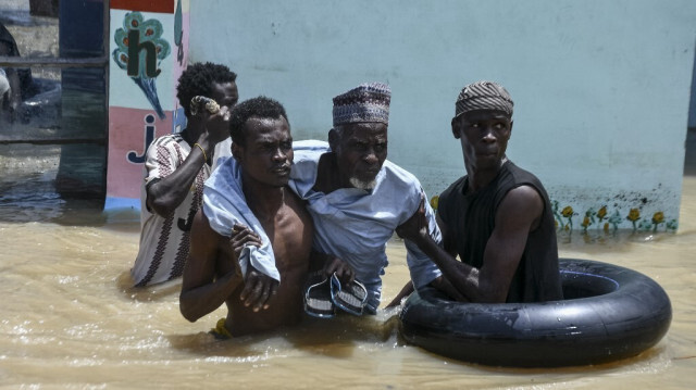 Des personnes aident un homme âgé à traverser les eaux de crue à Maiduguri le 12 septembre 2024. De graves inondations dans la ville de Maiduguri, au nord-est du Nigeria, ont fait au moins 30 morts et forcé 400 000 personnes à quitter leur domicile, ont indiqué des responsables le 11 septembre 2024.