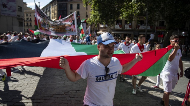 Des membres de "penas" (groupes festifs) participent à une manifestation sous le slogan "Palestine libre" sur le chemin des arènes pendant les fêtes de San Fermin à Pampelune, dans le nord de l'Espagne, le 11 juillet 2024. 