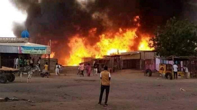 Un homme se tient debout alors qu'un incendie fait rage dans un marché aux bestiaux à al-Fasher, la capitale de l'État du Nord-Darfour au Soudan, le 1er septembre 2023, à la suite d'un bombardement par les forces paramilitaires de soutien rapide (RSF).