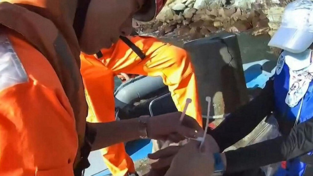 Des garde-côtes taïwanais attachant des liens en plastique autour des poignets d'un ressortissant chinois (en bleu), qui a été arrêté après s'être rendu sur l'îlot éloigné de Menghu dans le comté de Kinmen, près de Kinmen, le 14 octobre 2024.