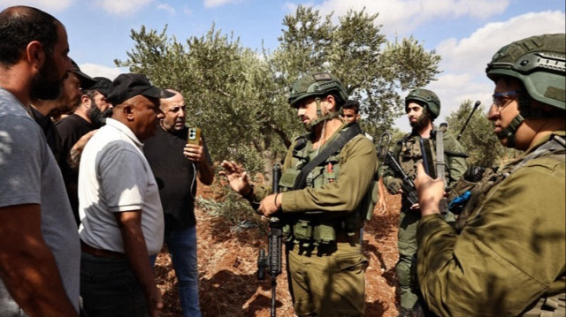 L'armée d'occupation ordonnent aux agriculteurs palestiniens et aux volontaires qui les aident de quitter le champ pendant la saison de la récolte des olives dans le village de Qusra, au sud de Naplouse en Palestine occupée, le 15 octobre 2024.