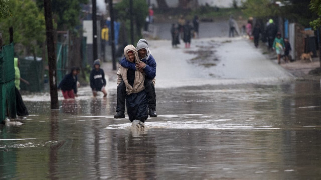 Un homme porte une personne âgée sur une route inondée lors de fortes inondations dues à une tempête à Sir Lowry's Village, près de Somerset West, le 25 septembre 2023. 