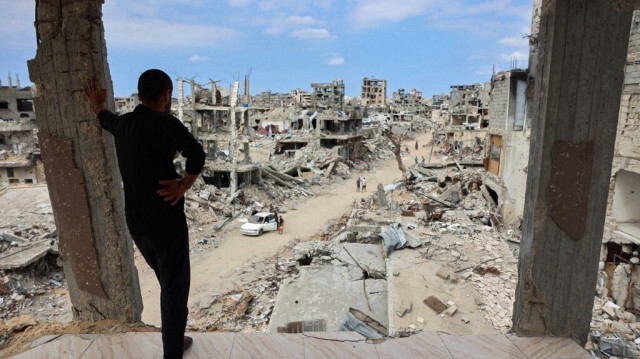 Depuis un bâtiment gravement endommagé, un Palestinien regarde le quartier de Shujaiya à Gaza, bombardé par l'armée d'occupation israélienne, le 7 octobre 2024.