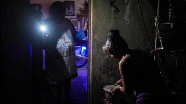 Une femme fait bouillir de l'eau tandis qu'une autre l'éclaire à l'aide d'un téléphone portable lors d'une panne nationale causée par une défaillance du réseau électrique à Matanzas, Cuba, le 18 octobre 2024. Des pannes techniques, des pénuries de carburant et une forte demande ont provoqué des défaillances constantes des centrales thermoélectriques du pays, obligeant le gouvernement à déclarer une urgence énergétique et à prendre des mesures telles que la fermeture d'écoles et d'usines.