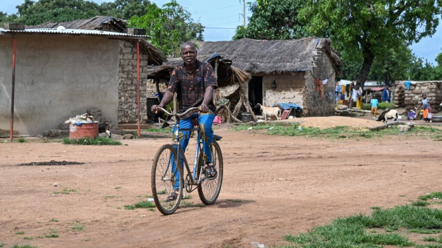 Un homme fait du vélo dans le village de Kafolo le 26 septembre 2024, quatre ans après une attaque terroriste dans le nord de la Côte d'Ivoire.