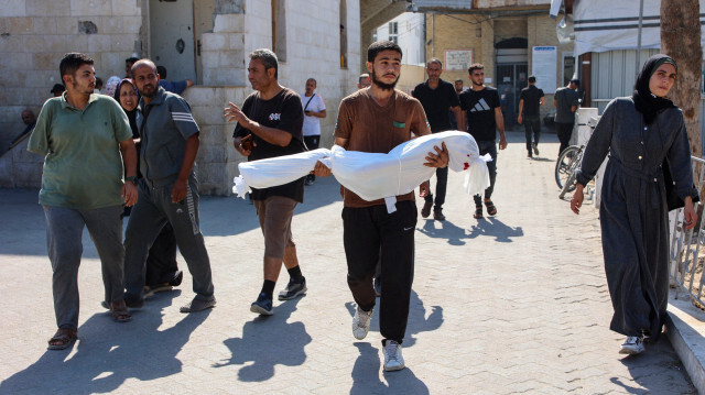 Un parent porte le corps enveloppé de Sama al-Debs, 10 ans, qui a été tuée lors d'une opération de l'armée israélienne dans le camp de réfugiés de Jabalia, dans le centre de la bande de Gaza, avant ses funérailles, le 18 octobre 2024, alors que la guerre entre Israël et le groupe militant palestinien Hamas se poursuit.