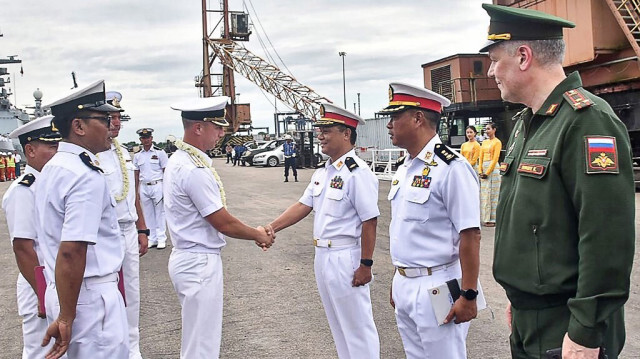 Un responsable militaire du Myanmar serrant la main d'un membre de la marine russe avant des exercices maritimes conjoints dans le port de Thilawa à Yangon, le 21 octobre 2024.