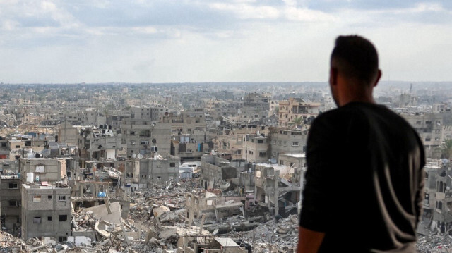 Un Palestinien se tient dans un immeuble gravement endommagé, observant les autres bâtiments détruits à Khan Yunis par l'armée d'occupation israélienne, dans le sud de la bande de Gaza, le 7 octobre 2024.