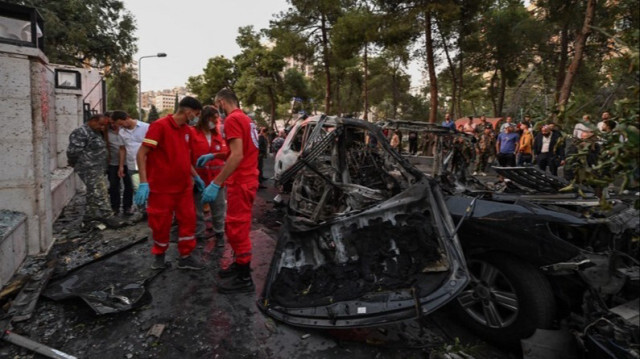 Les services d'urgence et de sécurité syriens inspectent l'épave d'une voiture où deux personnes ont été tuées et trois autres blessées lors d'une frappe aérienne israélienne à Damas, le 21 octobre 2024.