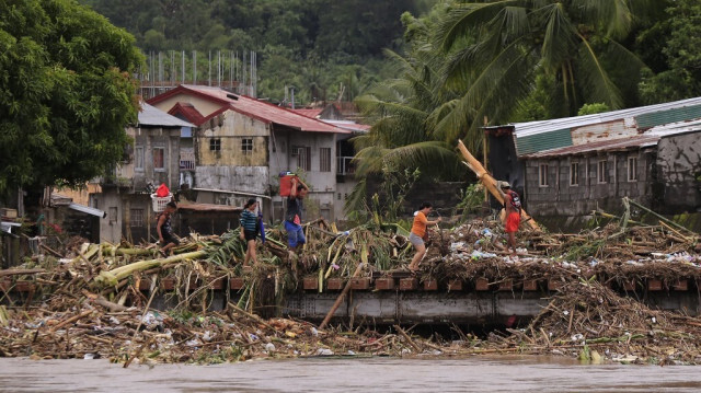 Des habitants traversent un pont rempli de débris en raison des fortes pluies provoquées par la tempête tropicale Trami dans la ville de Polangui, province d'Albay, au sud de Manille, le 23 octobre 2024.