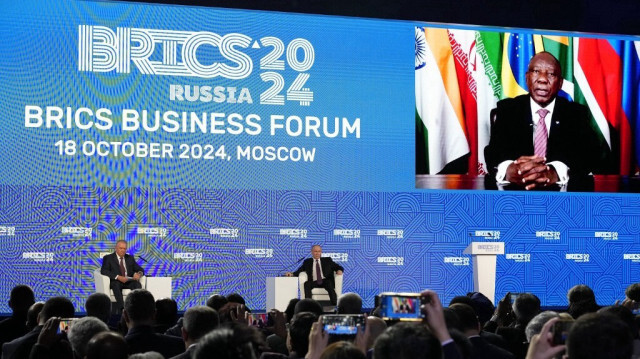 Le président russe Vladimir Poutine écoute le président sud-africain Cyril Ramaphosa alors qu'il apparaît sur un écran pour s'adresser aux participants d'un forum d'affaires des BRICS à Moscou, le 18 octobre 2024.