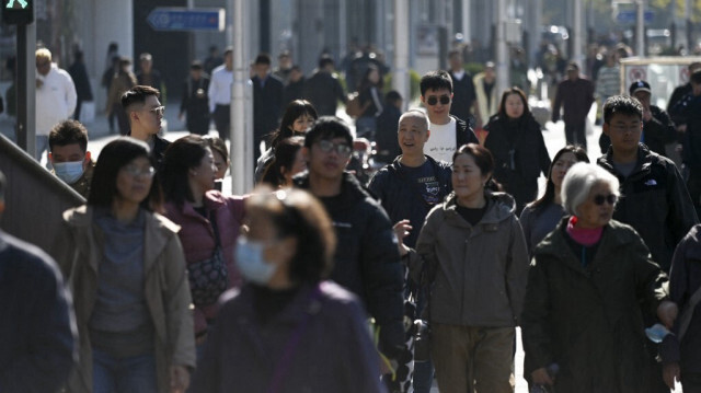 Des personnes traversent une rue dans un quartier d'affaires de Pékin, le 23 octobre 2024.