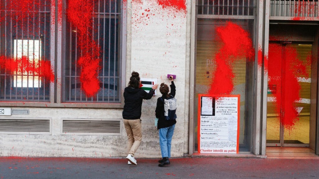 Des militants d'Action Justice Climat collent une pancarte représentant le drapeau national de la Palestine après avoir peint la façade de la banque multinationale française, place de la Bourse à Paris, le 24 octobre 2024.