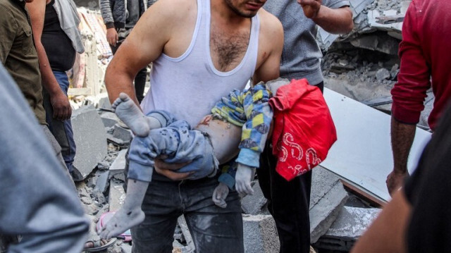 Un homme porte le corps d'un enfant qui a été récupéré dans les décombres après un bombardement israélien, au nord de la ville de Gaza, le 26 octobre 2024.