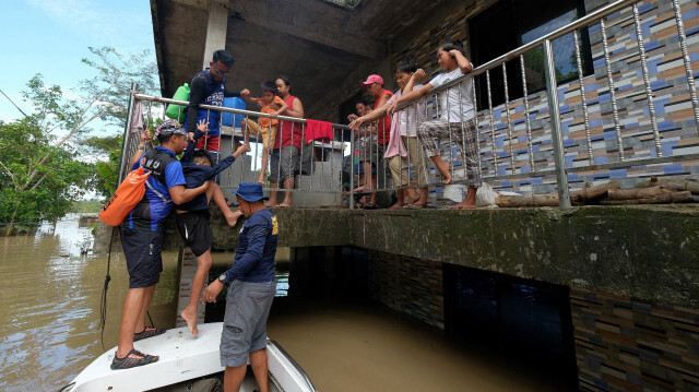 Des sauveteurs évacuent une famille de leur maison submergée par la tempête tropicale Trami dans la ville de Bula, province de Camarines Sur, au sud de Manille, le 26 octobre 2024. Dans la région de Bicol, durement touchée, les habitants bloqués sur les toits et les étages supérieurs de leurs maisons attendent toujours une aide désespérée, ont indiqué des responsables.