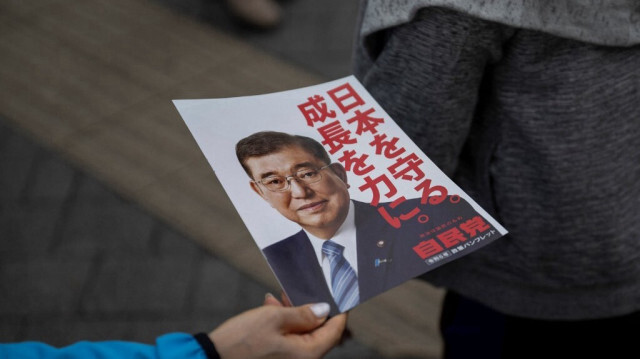 Un membre du personnel distribue des prospectus avec la photo du Premier ministre japonais Shigeru Ishiba avant son discours de campagne électorale à Tokyo le 26 octobre 2024.