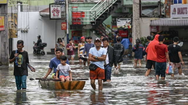 Des personnes pataugent dans une rue inondée par les fortes pluies provoquées par la tempête tropicale Trami à Cainta, dans la province de Rizal, à l'est de Manille, le 25 octobre 2024.