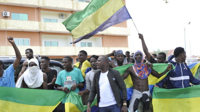 Des habitants brandissant des drapeaux nationaux du Gabon, jubilent à Libreville le 30 août 2023 après qu'un groupe d'officiers de l'armée gabonaise a annoncé à la télévision qu'ils mettaient "fin au régime actuel" et qu'ils annulaient les résultats officiels des élections qui avaient accordé un nouveau mandat au président vétéran Ali Bongo Ondimba. 