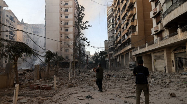 Des personnes photographient les dégâts causés par les frappes aériennes israéliennes qui ont visé la banlieue sud de Beyrouth, le 5 octobre 2024.