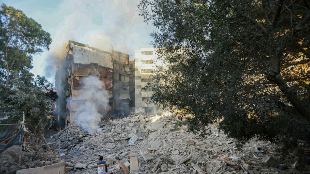 Un homme regarde la fumée qui s'échappe des décombres d'un bâtiment sur le site des frappes aériennes israéliennes de la nuit dans le quartier de Mreijeh, dans la banlieue sud de Beyrouth, le 4 octobre 2024.