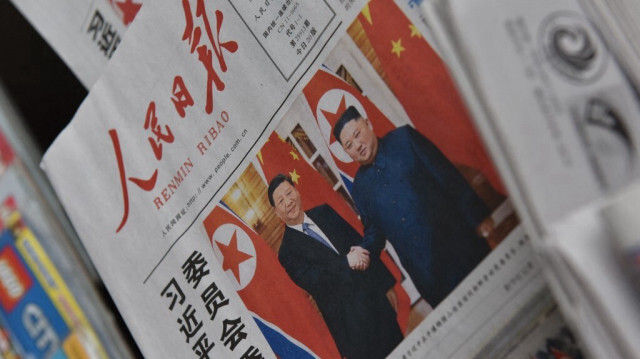 Un journal comportant une photo en première page du président chinois Xi Jinping (G) serrant la main du dirigeant nord-coréen Kim Jong Un à Pyongyang, est vu dans un kiosque à journaux à Pékin, le 21 juin 2019. 