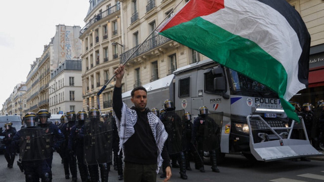 Un manifestant tient un drapeau palestinien devant des policiers anti-émeute du Corps républicain de sécurité (CRS) français lors d'un rassemblement organisée par l'organisation "France Palestine Solidarité" à Paris, le 27 mai 2024