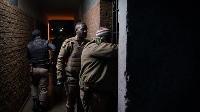 Des membres du Department of Correctional Service s'apprêtent à pénétrer dans un appartement lors d'une opération multidisciplinaire à Vrededorp, au nord-ouest de Johannesburg, le 2 octobre 2024. 