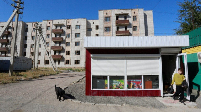 Un garçon sort d'une épicerie avec ses achats, près d'un bâtiment abandonné de plusieurs étages dans le village d'Ulken, situé sur les rives du lac Balkhash, à environ 400 kilomètres au nord d'Almaty, le 21 septembre 2024, lieu où la première centrale nucléaire du pays devrait être construite.