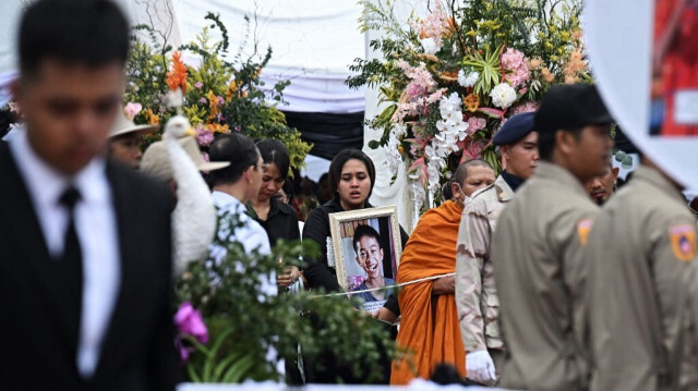 Des membres de familles endeuillées tiennent des portraits de leurs proches lors de la cérémonie de crémation des victimes de l'incendie d'un bus scolaire, qui marque les derniers rites funéraires bouddhistes à l'école Wat Khao Phraya Sangkharam à Uthai Thani, le 8 octobre 2024.