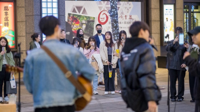 Des gens regardent des artistes de rue chanter dans une rue du district de Xinyi à Taipei, le 16 janvier 2024.