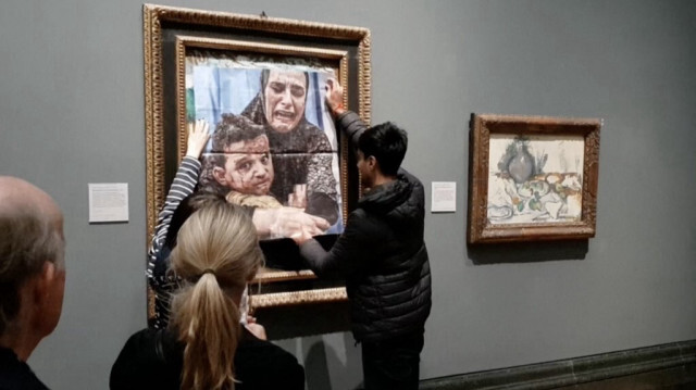 Un militant de Youth Demand place la photo d'une mère et de son enfant de Gaza sur l'œuvre de Picasso intitulée "Maternité", à la National Gallery, dans le centre de Londres, le 9 octobre 2024.