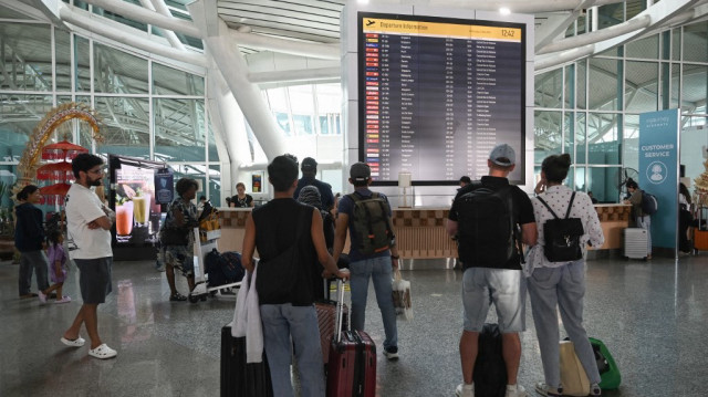 Des passagers regardent un tableau électronique affichant les vols annulés après que le volcan voisin du mont Lewotobi Laki-Laki a catapulté une tour de cendres à des kilomètres dans le ciel, à l'aéroport international Ngurah Rai de Tuban près de Denpasar, sur l'île balnéaire de Bali, en Indonésie, le 13 novembre 2024.