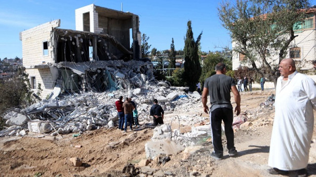 Des Palestiniens regardent les forces israéliennes, accompagnées de bulldozers, faire une descente et démolir une maison palestinienne au motif qu'elle était "sans permis"  en Palestine occupée.