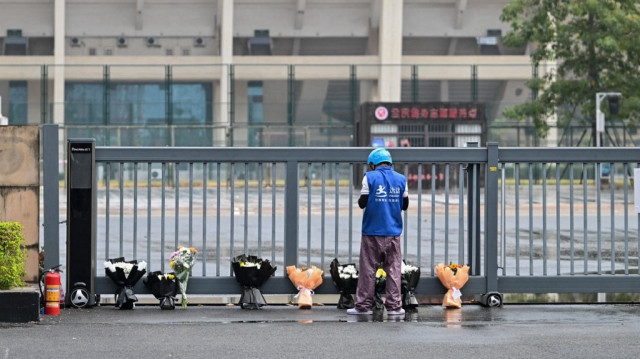 Un livreur dépose des bouquets de fleurs commandés en ligne sur un mémorial improvisé à l'extérieur du Centre sportif de Zhuhai à Zhuhai, dans la province de Guangdong, dans le sud de la Chine, le 13 novembre 2024, deux jours après que 35 personnes ont été tuées lorsqu'un homme a foncé dans la foule au volant d'une voiture, dans l'un des événements les plus meurtriers de ces dernières années dans le pays.