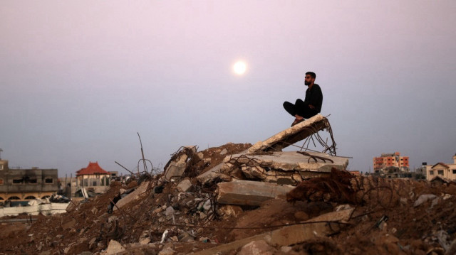 La pleine lune se lève alors qu'un homme est assis sur un tas de décombres dans le camp de réfugiés d'al-Bureij, dans le centre de la bande de Gaza, le 15 novembre 2024, alors que la guerre entre Israël et le groupe militant du Hamas se poursuit.