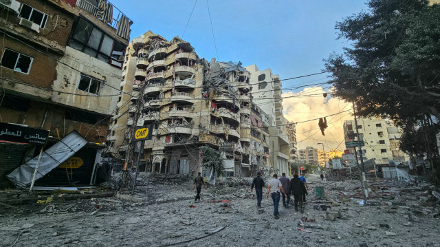 Des personnes marchent au milieu des destructions, à la suite des frappes aériennes israéliennes qui ont visé le quartier de Haret Hreik dans la banlieue sud de Beyrouth, le 16 novembre 2024, alors que la guerre entre Israël et le Hezbollah se poursuit.