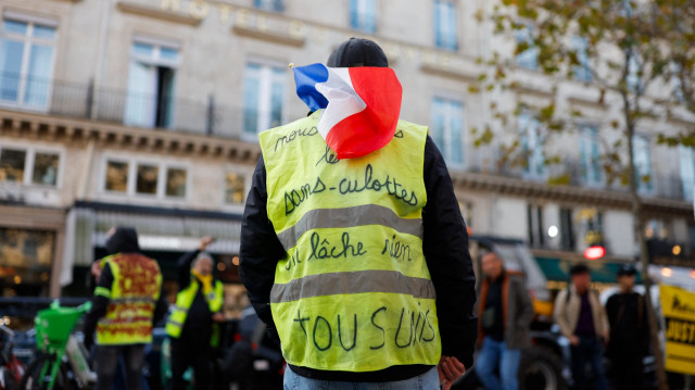 Un manifestant brandissant un gilet jaune et un drapeau français participe à une manifestation à l'occasion du 6e anniversaire du mouvement des Gilets Jaunes, place Colette à Paris, le 16 novembre 2024.